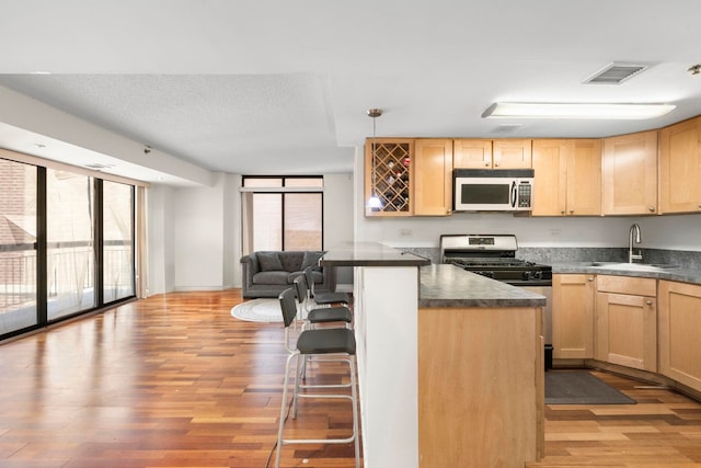 700 1st St Unit 6D, Hoboken, NJ 07030 - kitchen with light brown cabinetry, light wood finished floors, a kitchen bar, and dark countertops