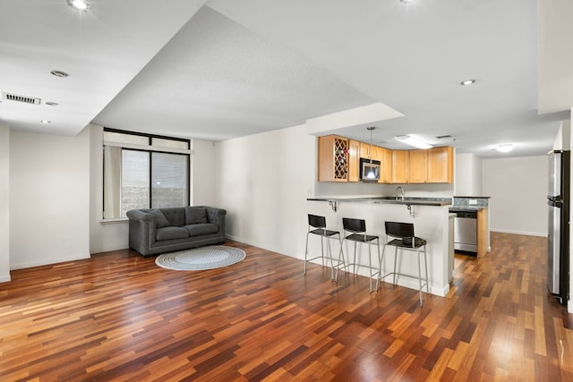 700 1st St Unit 6D, Hoboken, NJ 07030 - kitchen featuring stainless steel appliances, a peninsula, wood finished floors, a breakfast bar area, and light brown cabinets