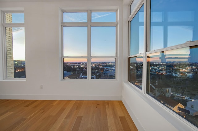 spare room with a view of city, baseboards, and light wood finished floors