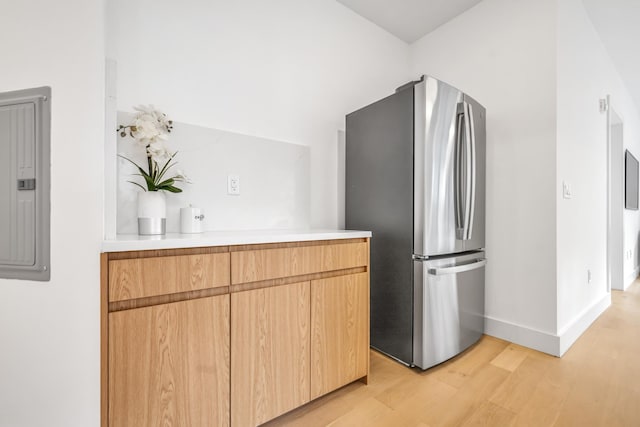 kitchen with electric panel, baseboards, freestanding refrigerator, light countertops, and light wood-style floors