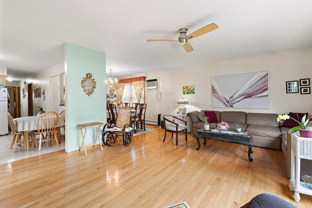 living area with ceiling fan with notable chandelier, a wall mounted air conditioner, and hardwood / wood-style floors