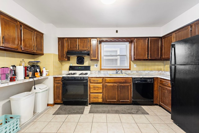 kitchen featuring black appliances, light countertops, under cabinet range hood, and a sink