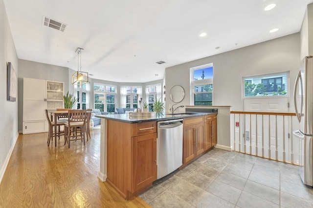 1200 Grand St Unit 220, Hoboken, NJ 07030 - kitchen with stainless steel appliances, brown cabinetry, recessed lighting, dark countertops, and decorative light fixtures