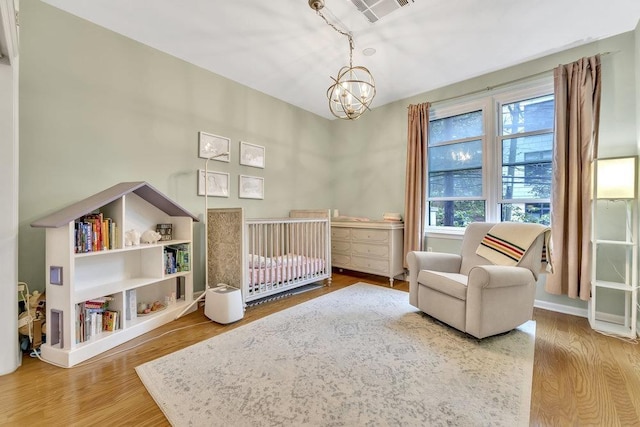 1200 Grand St Unit 220, Hoboken, NJ 07030 - bedroom featuring a nursery area, a chandelier, and wood finished floors