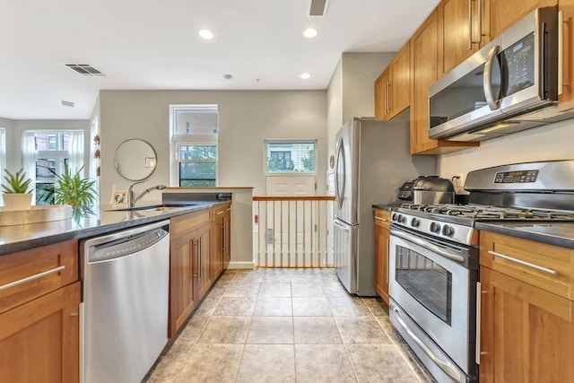 1200 Grand St Unit 220, Hoboken, NJ 07030 - kitchen with stainless steel appliances, dark countertops, brown cabinets, healthy amount of natural light, and recessed lighting