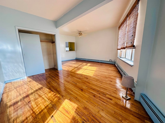 unfurnished bedroom featuring beamed ceiling, a closet, light hardwood / wood-style flooring, and a baseboard heating unit