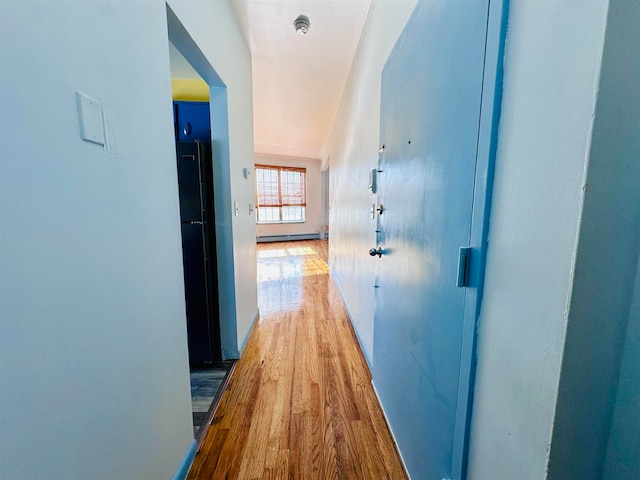 corridor featuring a baseboard radiator and light wood-type flooring