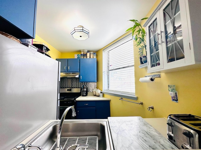 kitchen featuring blue cabinetry, sink, stainless steel range, and tasteful backsplash