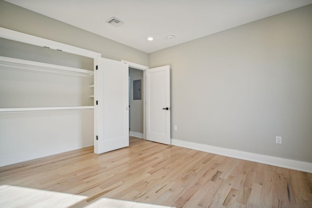 unfurnished bedroom featuring electric panel, light wood-type flooring, and a closet