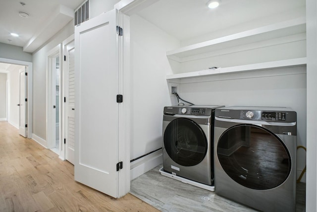 laundry room featuring washer and clothes dryer and light wood-type flooring