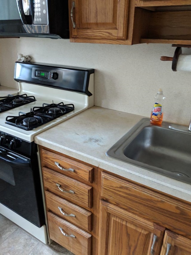 kitchen featuring sink, range with gas stovetop, and light tile patterned floors