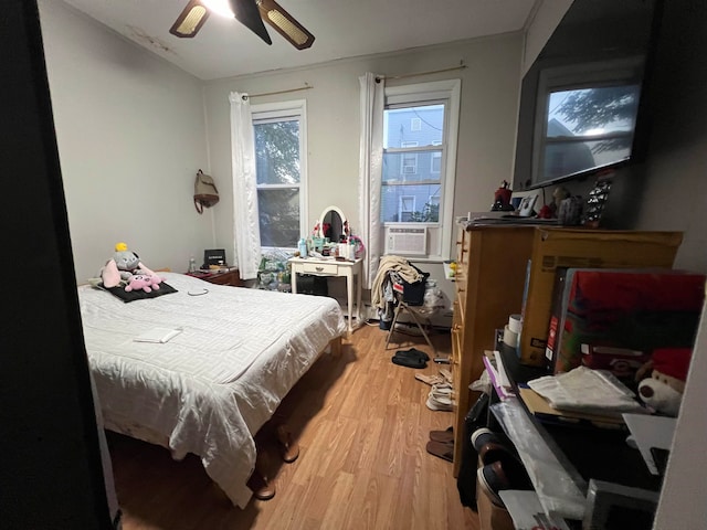 bedroom with cooling unit, hardwood / wood-style floors, and ceiling fan