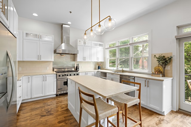 297 Montgomery St Unit 2, Jersey City, NJ 07302 - kitchen with wall chimney exhaust hood, appliances with stainless steel finishes, a breakfast bar, decorative backsplash, and recessed lighting