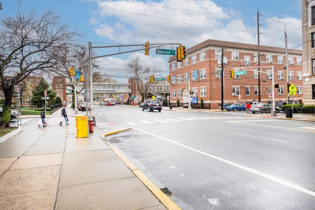 view of street with traffic lights, street lighting, sidewalks, curbs, and traffic signs