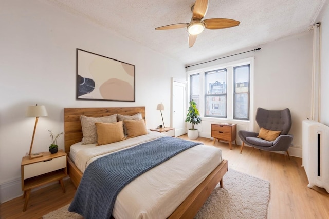 bedroom featuring a textured ceiling, radiator heating unit, and light wood finished floors
