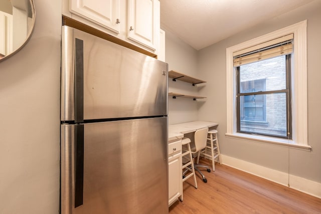 office area featuring baseboards, light wood-style flooring, and built in desk