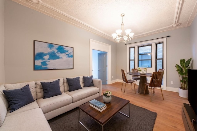 living area featuring baseboards, a textured ceiling, light wood-style flooring, and a notable chandelier