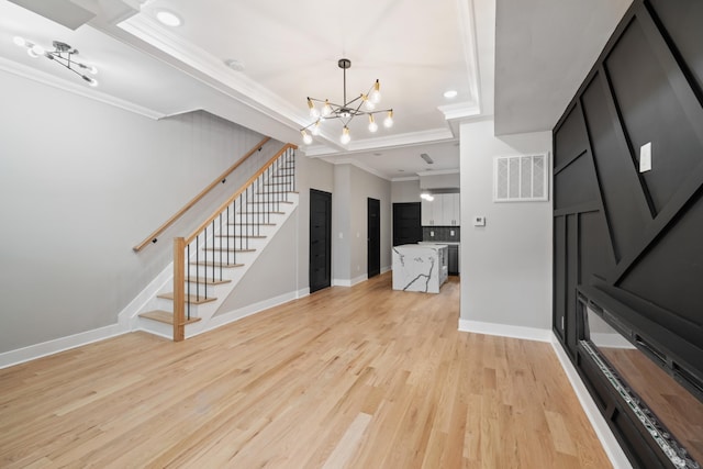 unfurnished living room with an inviting chandelier, light hardwood / wood-style floors, and crown molding