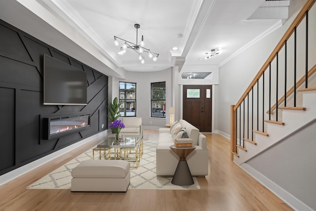 living room featuring a fireplace, a chandelier, crown molding, and light hardwood / wood-style flooring