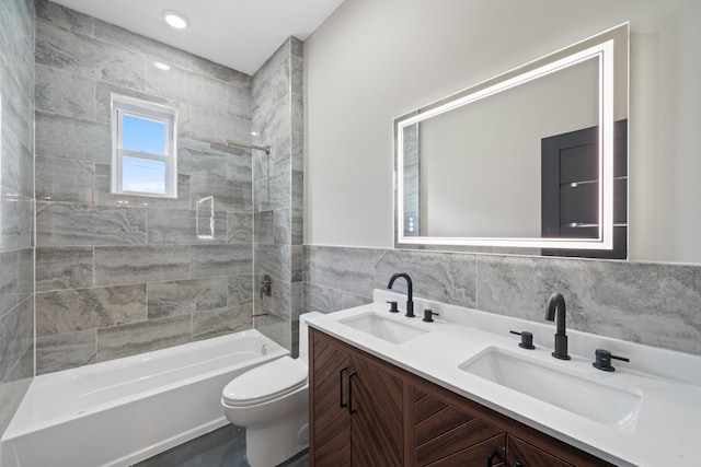 full bathroom with toilet, vanity, tile walls, and tiled shower / bath combo