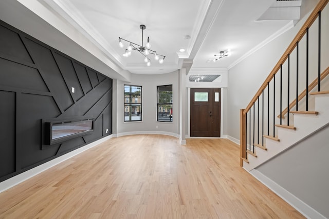 foyer entrance featuring a chandelier, ornamental molding, and light hardwood / wood-style floors