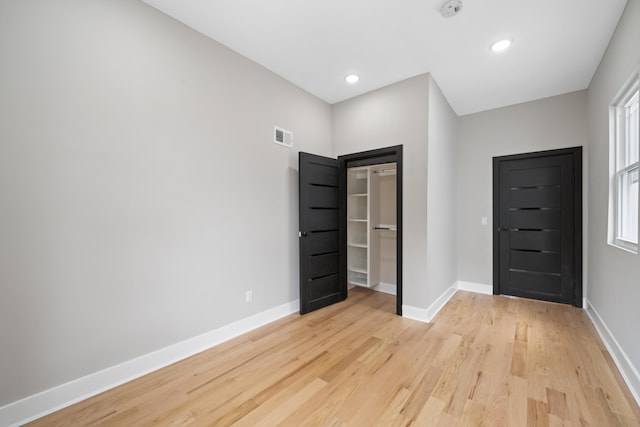 unfurnished bedroom featuring light hardwood / wood-style floors, a closet, and multiple windows