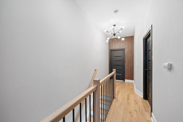 corridor with an inviting chandelier and light hardwood / wood-style flooring