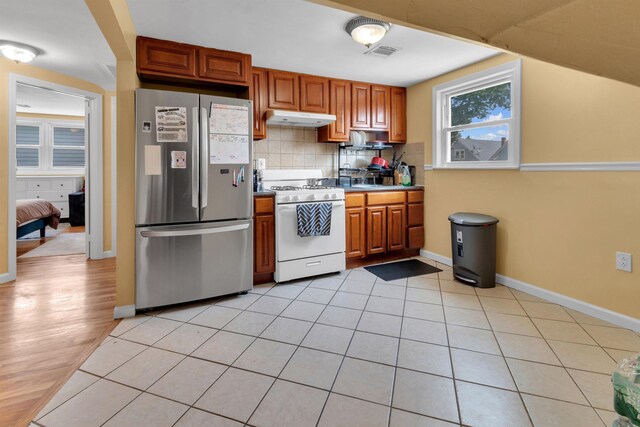 280 Highland Ave Unit 3, Kearny, NJ 07032 - kitchen featuring freestanding refrigerator, white gas range oven, under cabinet range hood, tasteful backsplash, and brown cabinets