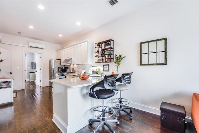 351 5th St Unit 3, Jersey City, NJ 07302 - kitchen featuring under cabinet range hood, white cabinetry, a kitchen bar, recessed lighting, and light countertops