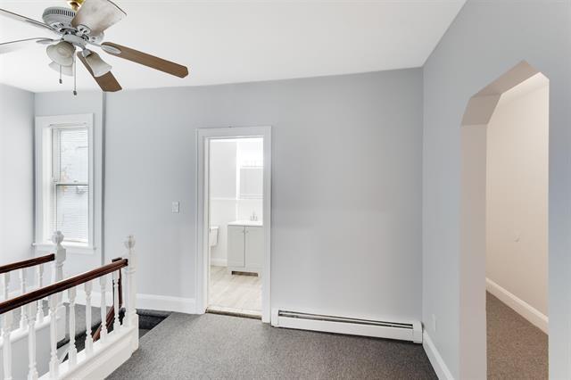 1406 8th St Unit 2, North Bergen, NJ 07047 - unfurnished room featuring baseboard heating, carpet flooring, ceiling fan, and arched walkways