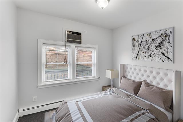1406 8th St Unit 2, North Bergen, NJ 07047 - bedroom featuring a baseboard heating unit, an AC wall unit, and carpet flooring