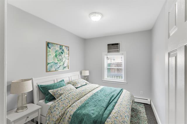 1406 8th St Unit 2, North Bergen, NJ 07047 - carpeted bedroom featuring a baseboard heating unit, an AC wall unit, and baseboards
