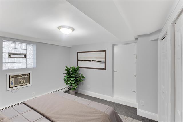 1406 8th St Unit 2, North Bergen, NJ 07047 - bedroom with baseboards, a wall unit AC, and a baseboard heating unit