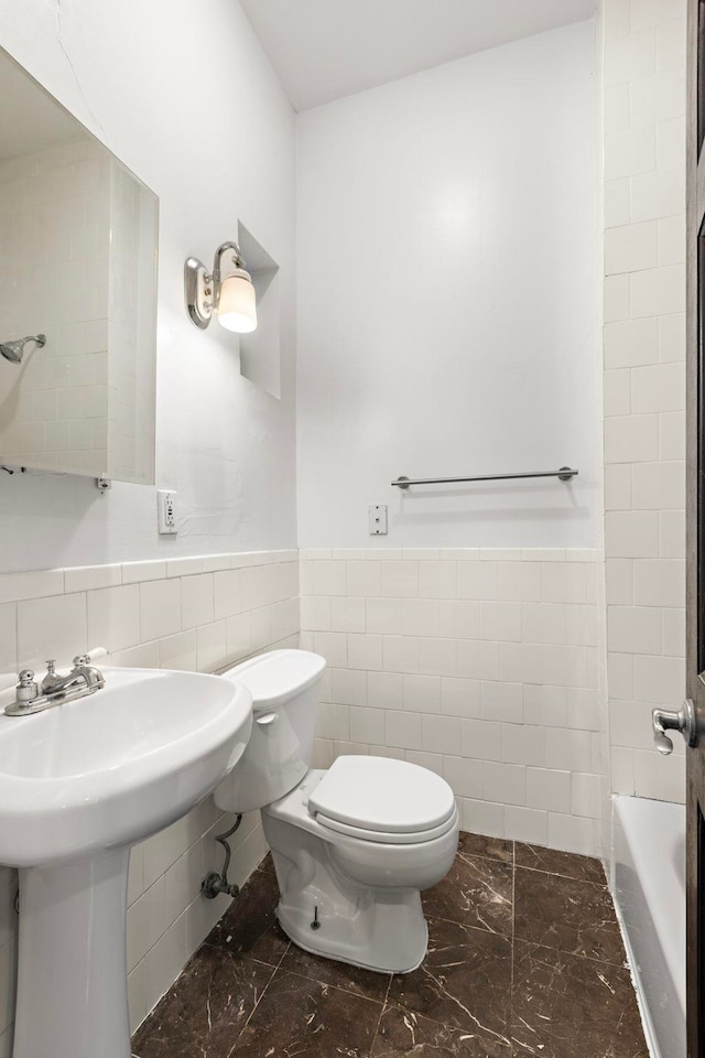 bathroom with sink, toilet, and tile walls