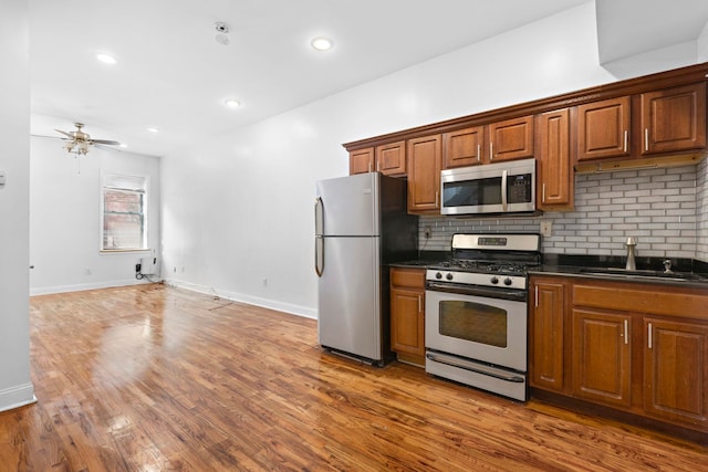 kitchen with tasteful backsplash, wood-type flooring, stainless steel appliances, sink, and ceiling fan