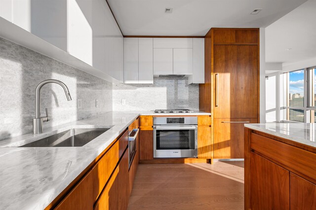 75 Park Ln S Unit 1912, Jersey City, NJ 07310 - kitchen with stainless steel appliances, a sink, tasteful backsplash, and brown cabinetry