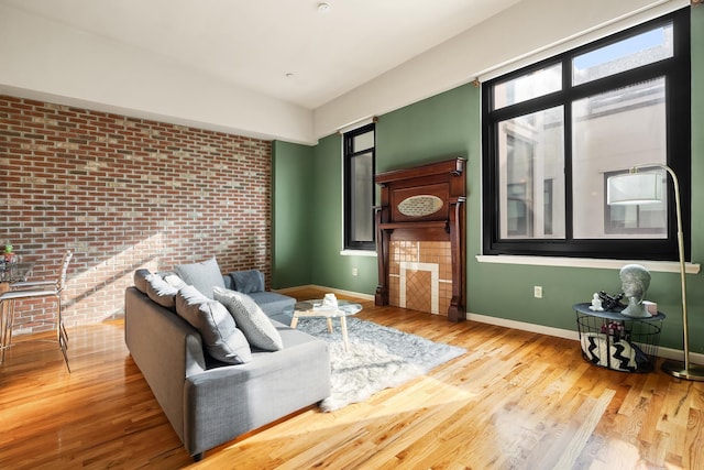 living area with baseboards, wood finished floors, and brick wall