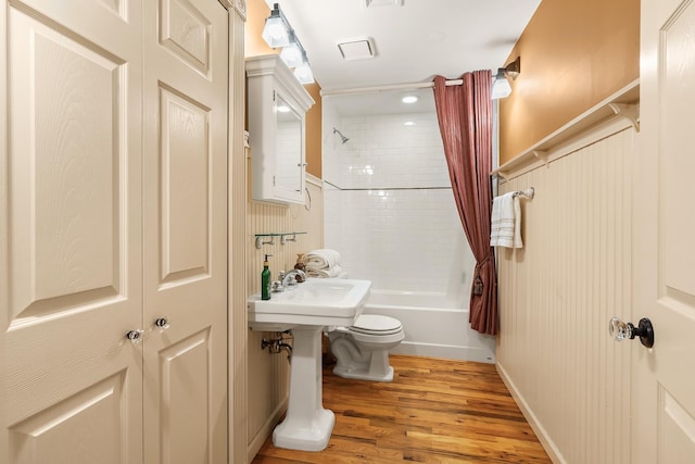 bathroom with toilet, shower / bath combo, and wood finished floors