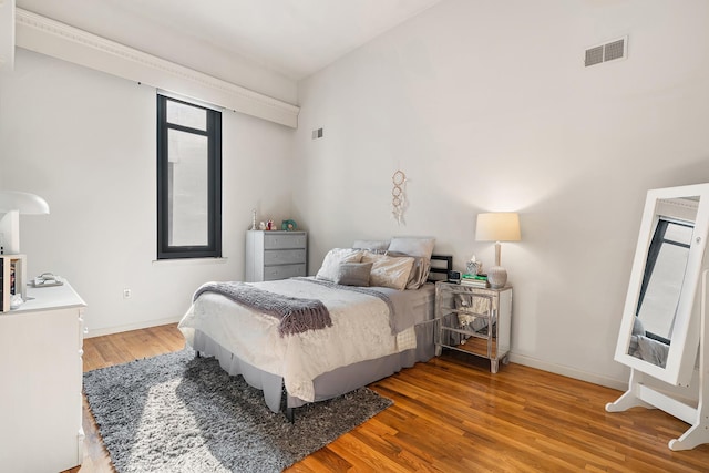 bedroom with wood finished floors, visible vents, and baseboards