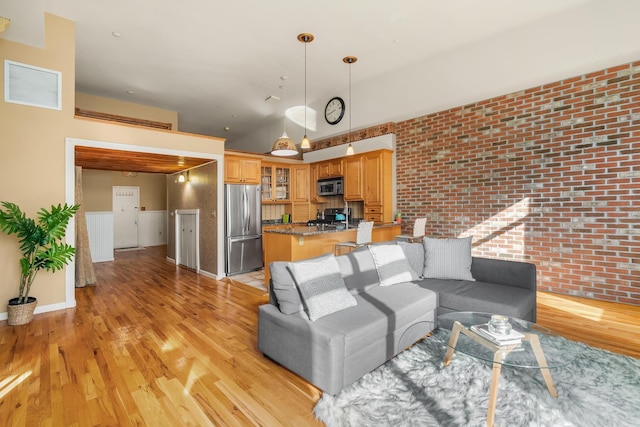 living area with visible vents, brick wall, baseboards, and light wood-style floors