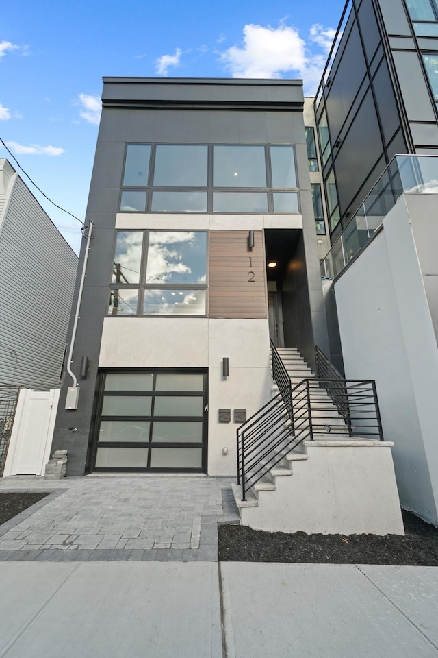 view of front of property with decorative driveway, an attached garage, and stucco siding