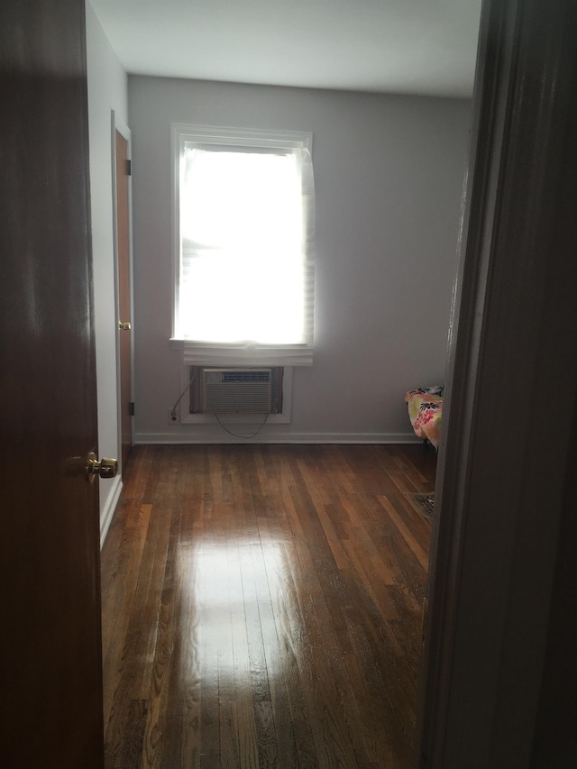 empty room with a wall mounted air conditioner and dark hardwood / wood-style floors