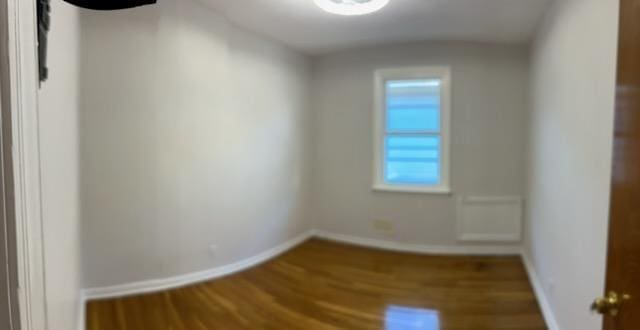 spare room featuring baseboards and wood finished floors