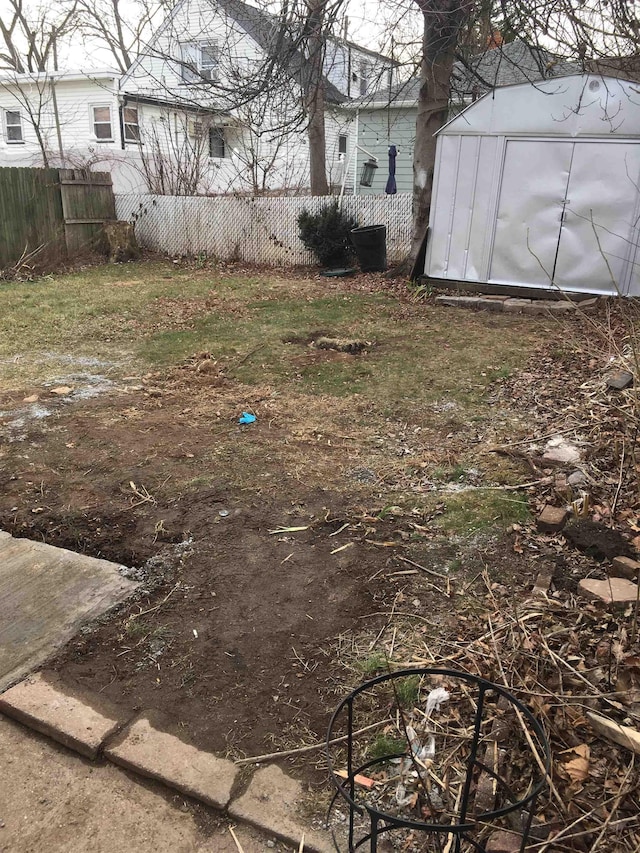 view of yard with an outbuilding, a storage shed, and fence