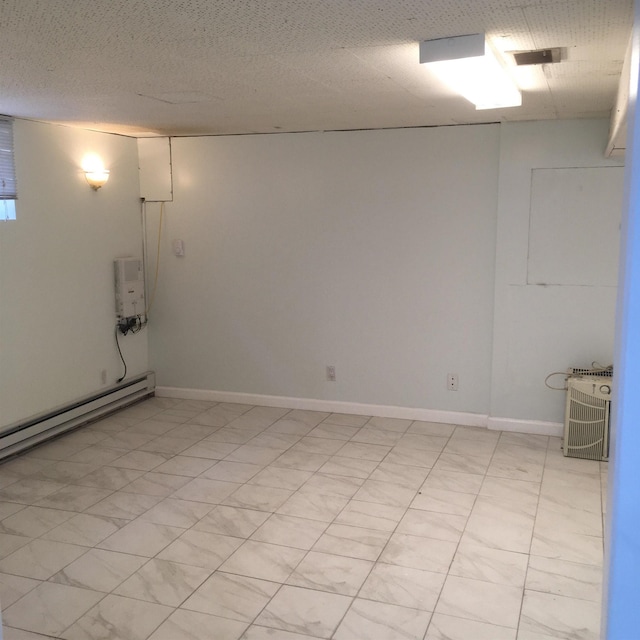 unfurnished room with baseboard heating, visible vents, a textured ceiling, and baseboards