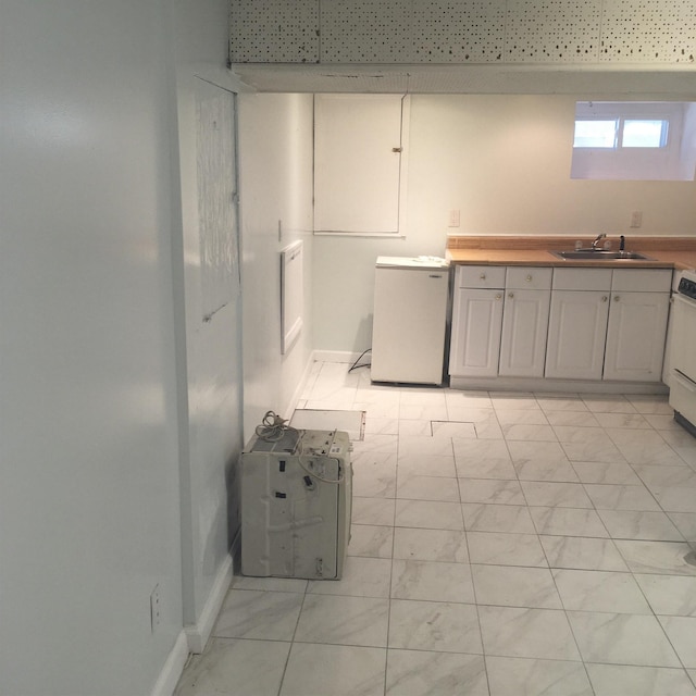 kitchen with refrigerator, a sink, and baseboards