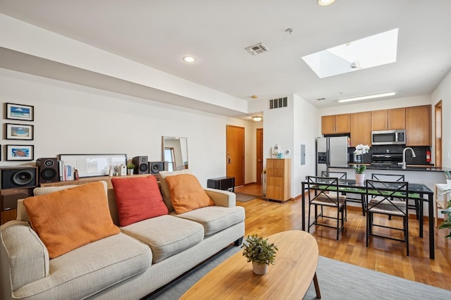 living area featuring visible vents, recessed lighting, a skylight, and light wood-type flooring
