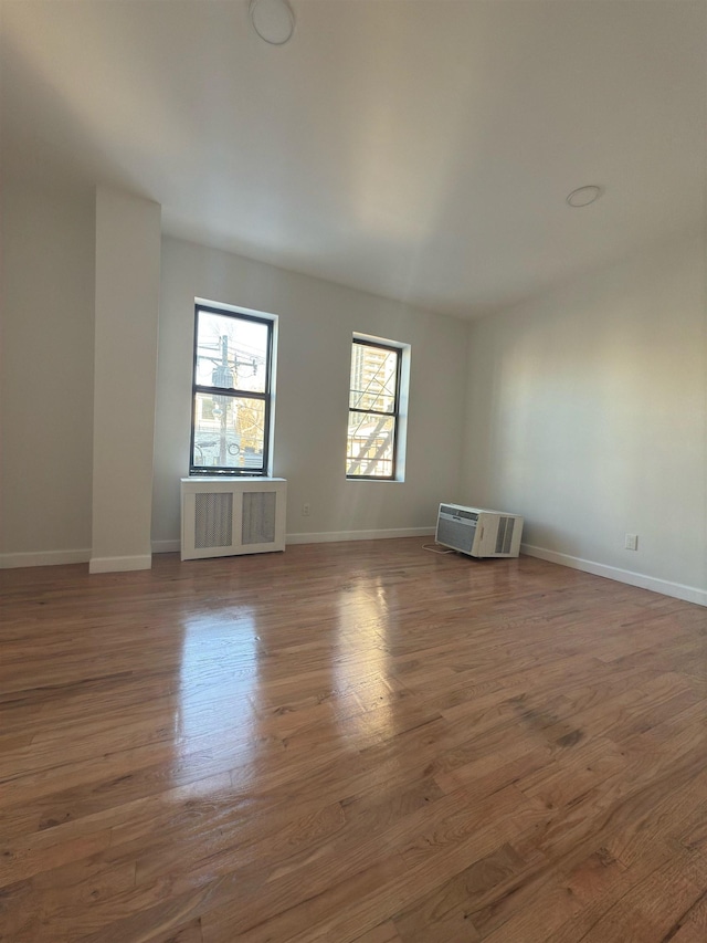 spare room featuring radiator, baseboards, and wood finished floors