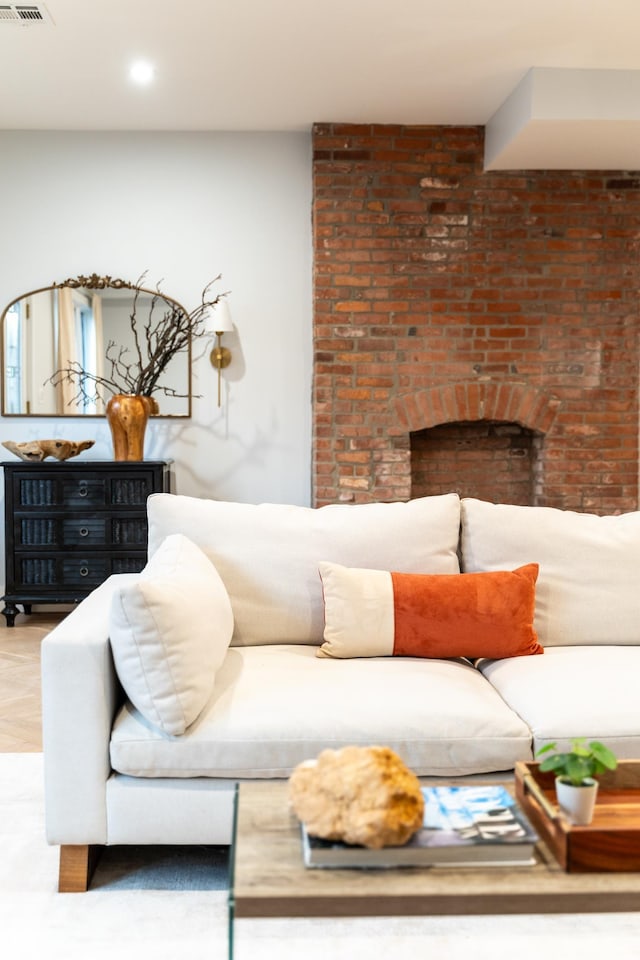 living room with a brick fireplace, wood finished floors, and visible vents