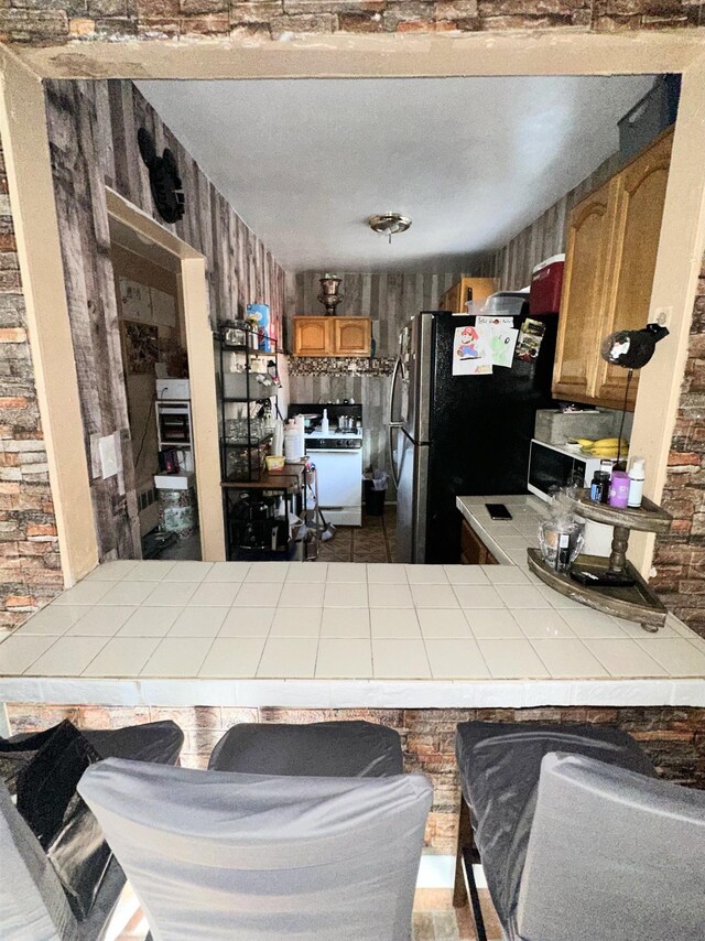 552 38th St Unit 3, Union City, NJ 07087 - kitchen with tile countertops, freestanding refrigerator, brown cabinetry, dishwashing machine, and a peninsula